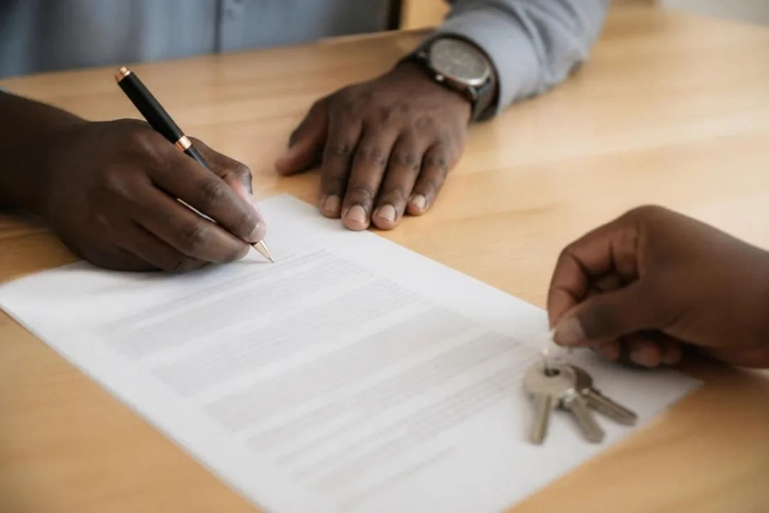 Signature d'un contrat de sous-location et remise des clés, vue en gros plan sur les mains