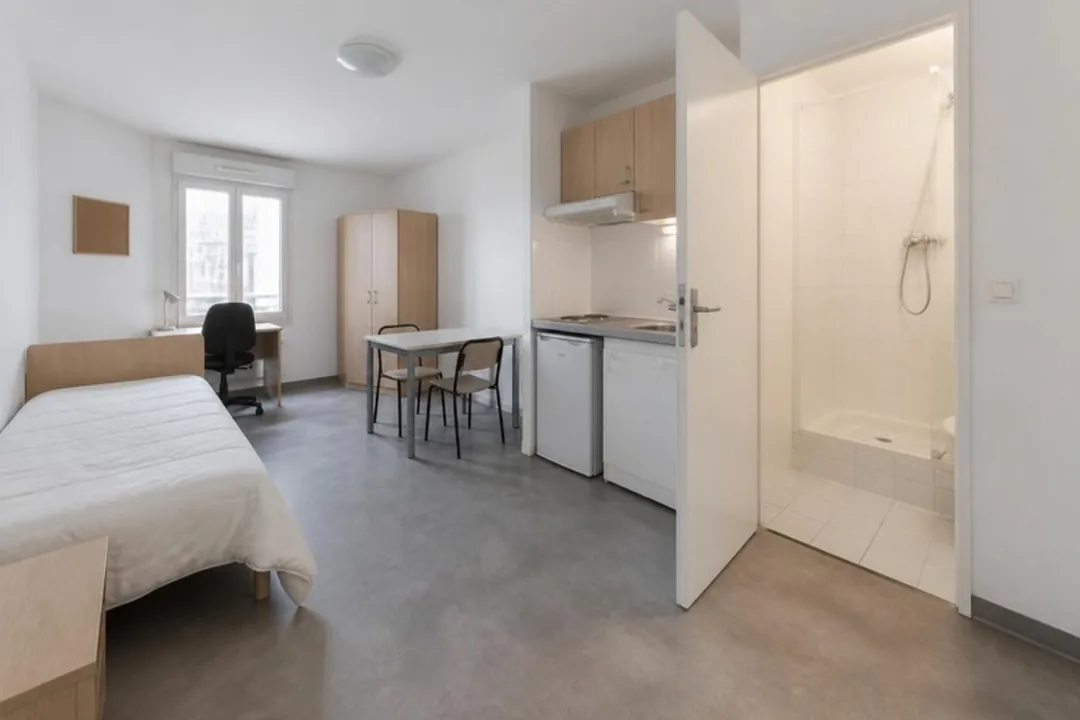 Logement meublé prêt à accueillir un jeune : lit, bureau, armoire, coin cuisine équipé et salle d'eau avec douche